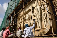 a banner image showing a carved stone image being maintained by a number of workmen